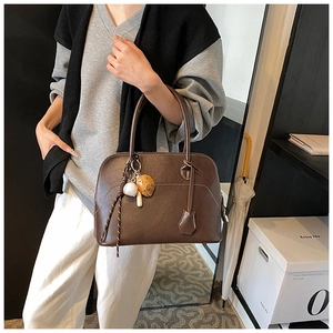 Detail of a dark brown PU leather dome bag with white stitching and baseball charm