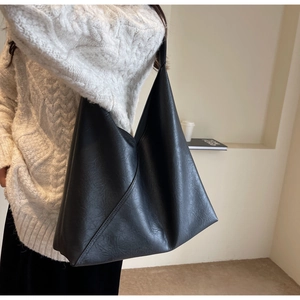 Close-up of black slouchy tote bag with vintage leather texture and diagonal stitching
