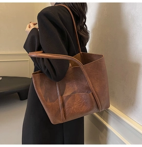 Detail of vintage brown PU leather tote bag with vertical stitching and long shoulder strap