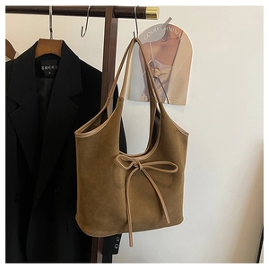 Détail du sac cabas en daim marron avec nœud décoratif et finitions des poignées