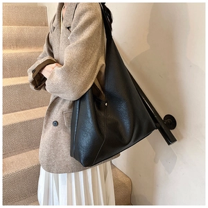 Fashionable black PU leather hobo bag with side rivet details shown on female shoulder