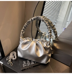 Macro shot of silver pleated cloud bag with metallic finish and ruffled handle detail