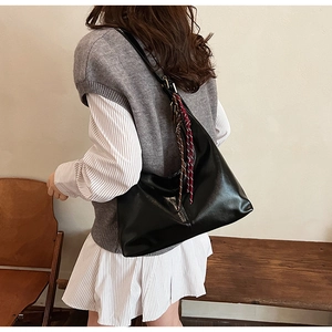 Minimalist black crescent shoulder bag with brown silk scarf detail on the strap