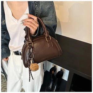 Detail einer dunkelbraunen PU-Leder-Handtasche mit einem süßen Elefanten Plüschanhänger