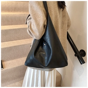 Fashionable black large capacity PU leather shoulder bag on a model in interior setting