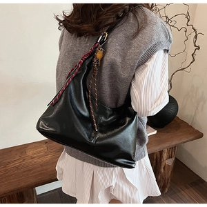 Detail view of black PU leather hobo bag with colorful woven rope charms for fall season
