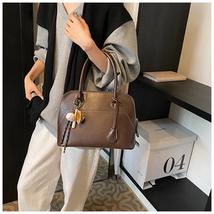 Detail view of deep brown pebbled leather shell bag with baseball glove charms