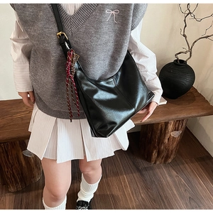 Detailed view of black PU leather hobo bag with gold buckle and woven charm strap