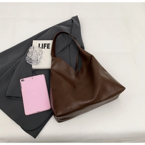 Detailed texture of dark brown leather tote bag with elegant minimalist folded design