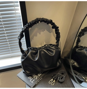 Detailed view of black pleated cloud bag with detachable strap and ruched handle