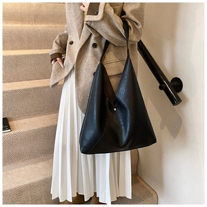 Detail of minimalist black PU leather tote bag showing fine texture and rivet design