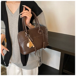 Detail of a dark coffee Boston bag showing leather texture and sports pendant decor