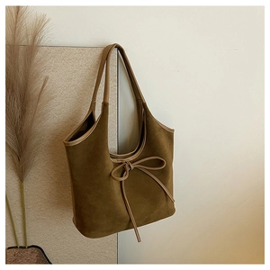 Détail d'un sac hobo en daim marron avec un nœud en cuir et des bordures contrastées
