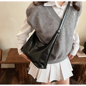 Detail of minimalist black leather crescent crossbody bag with adjustable strap on model