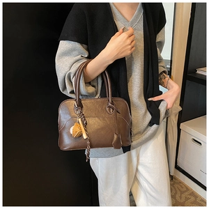 Detail of retro dark brown PU leather shell bag with baseball charm and top handles