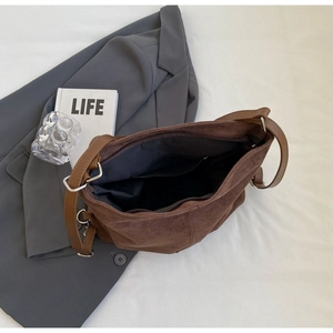 Detailed view of dark brown faux suede bag interior featuring a black lining and zip pocket