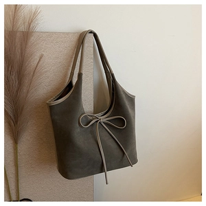 Détail du sac cabas gris mat avec nœud délicat et texture en cuir suédé doux