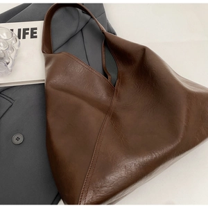 Detailed close-up of dark brown soft leather tote bag showing textured finish and V-shaped opening