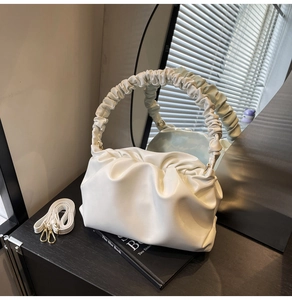 Detail of white ruched cloud bag with detachable strap and elegant gold metal hooks