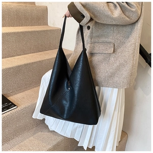 Detail view of black lychee grain leather tote bag showing soft texture and side stitching