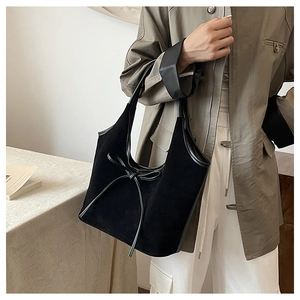 Détail du sac cabas en daim noir avec nœud décoratif et finitions en cuir lisse