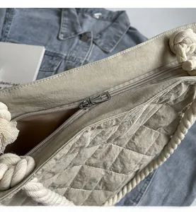 Detail of smooth metal zipper and quilted fabric on khaki tote bag with rope handle