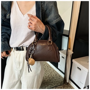 Detailansicht der dunkelbraunen Boston-Tasche mit Retro-PU-Textur und gewebtem Anhänger