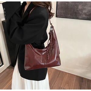 Detail of burgundy hobo shoulder bag with glossy finish and braided rope accent