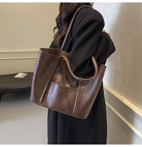 Detail of dark brown PU leather tote bag showing textured surface and large front pocket