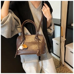 Close-up of a brown PU leather shoulder bag featuring a unique baseball theme keychain