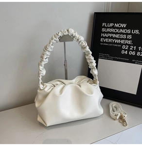 Detail of white pleated cloud bag showing ruched handle and detachable shoulder strap