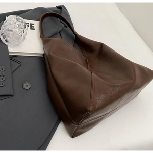 Detail view of brown leather hobo tote bag with lychee texture and stitched seam