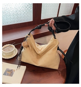 Gros plan d'un sac cabas en daim beige avec des anses en corde noire et un pendentif hibou