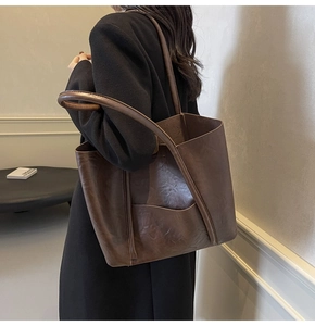 Detail of dark brown faux leather tote bag with lychee texture and crescent side pocket