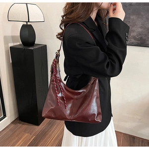 Detail view of burgundy PU leather hobo bag with red and white woven lanyard strap
