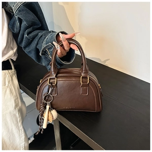 Detailansicht der braunen PU-Leder-Bostontasche mit Baseball-Anhänger und Goldteilen