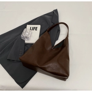 Flat lay of a large dark brown leather tote bag with a soft texture and wide shoulder strap