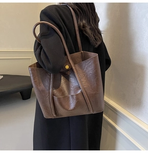 Detail of dark brown faux leather tote bag with magnetic clasp on a female model