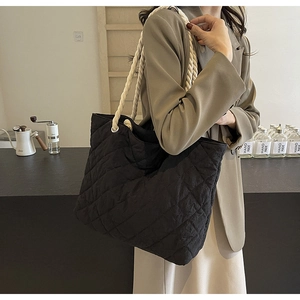 Detail of black quilted tote bag with chunky cream rope strap on casual blazer outfit