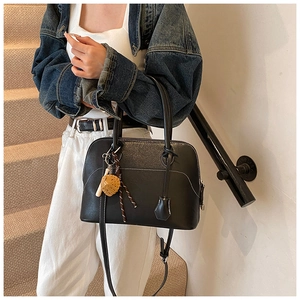 Detail of black pebbled PU leather shell bag with white contrast stitching and smile charm