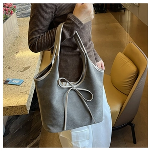 Détails du nœud décoratif et texture en daim sur ce sac cabas gris élégant