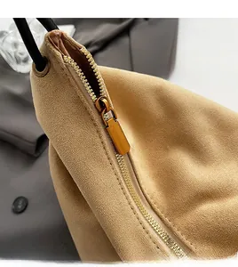 Détail du zip doré et des coutures sur un sac bandoulière en daim de couleur kaki