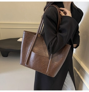 Detail showing the vintage dark brown pleated leather texture and slim shoulder straps