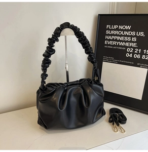 Detail of black pleated cloud bag with matte leather texture and adjustable shoulder strap