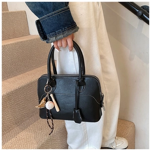 Detail of black PU leather bag with white contrast stitching and baseball charm