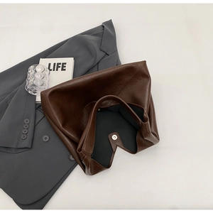 Detail shot of a dark brown PU leather tote bag with a magnetic snap button closure