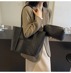 Chic black PU leather tote bag with vintage texture and matching pouch shown on a model