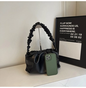 Detail showing black ruched cloud bag texture with smartphone for size comparison
