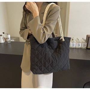 Chic black quilted tote bag with white rope handles shown in a lifestyle street setting