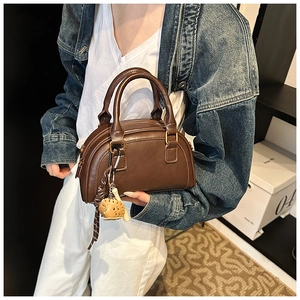 Detailansicht der braunen PU-Ledertasche mit Vintage-Design und Schweinchen-Anhänger